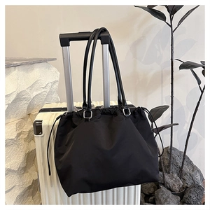 Detail of black drawstring tote bag on suitcase with silver metal hardware accents