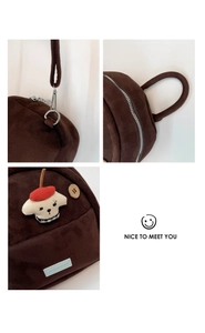 Detailed embroidery of a white puppy on a dark brown plush backpack with silver zip details