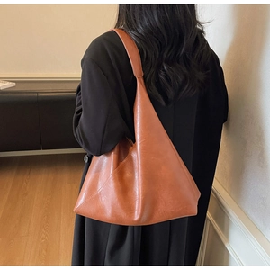 Detail of caramel faux leather tote bag showing vintage texture and wide shoulder strap