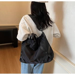 Große schwarze Reisetasche aus Nylon mit Kreuz-Gurtband und verstellbarem Schultergurt im Detail