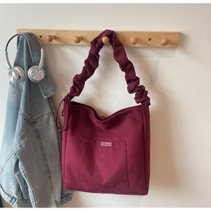 Detail of burgundy tote bag showing soft suede texture and ruched shoulder strap detail