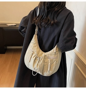 Detail of light green pleated croissant bag featuring woven drawstring and adjustable strap
