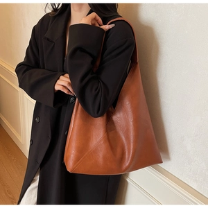 Detailed view of brown faux leather hobo bag with stitching texture on a female model