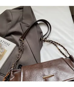 Detail of dark brown lychee textured shoulder bag with gold metal trim and chain strap