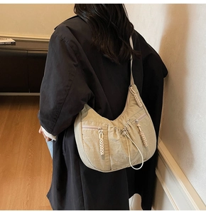 Rear view of a beige nylon crescent bag featuring pleated details and braided zip pullers