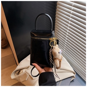 Détail d'un petit sac à main noir brillant avec un charmant pendentif ours en peluche