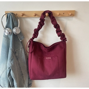 Detail of burgundy tote bag with pleated cloud shoulder strap and square front pocket