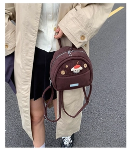 Detail of a brown corduroy mini backpack with wooden buttons and a cute dog patch