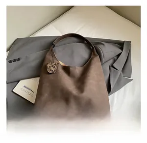Detail of dark brown matte leather tote bag with a leopard print charm accessory