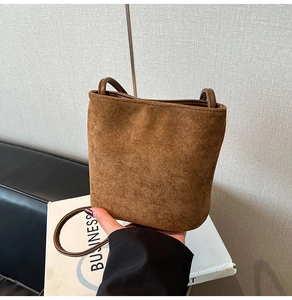 Detailed view of caramel brown suede bucket bag texture and slim leather shoulder strap