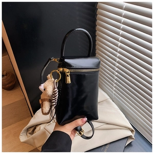 Détail d'un mini sac bandoulière en cuir noir avec ferrures dorées et breloque ours en peluche