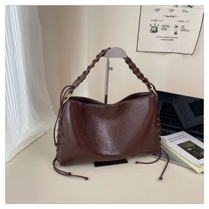 Détail d'un sac hobo marron brillant en cuir PU avec lacets latéraux et sangle tressée