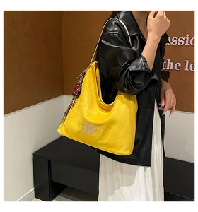 Close-up of yellow tote bag with Nice to meet you embroidery and cartoon bear detail