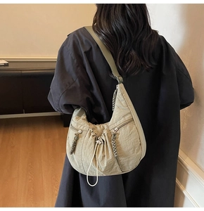 Close-up of olive green pleated crescent crossbody bag featuring drawstring closure details