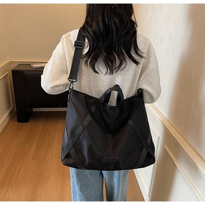Rückansicht eines Models mit großer schwarzer Nylon-Reisetasche und breitem Gurt