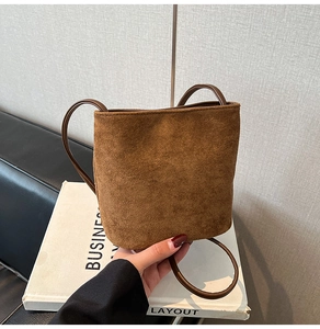 Detail of caramel brown suede mini bucket bag with slender leather shoulder straps
