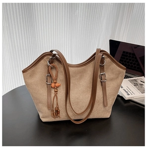 Detail of khaki tote bag with brown leather trim and unique gourd tassel pendant