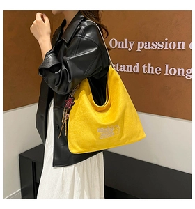 Close-up of bright yellow corduroy tote bag with cartoon embroidery and bear charm