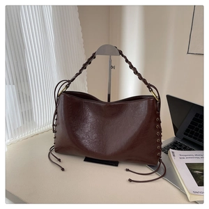 Vue détaillée d'un sac en cuir marron foncé avec poignées tressées et cordons latéraux