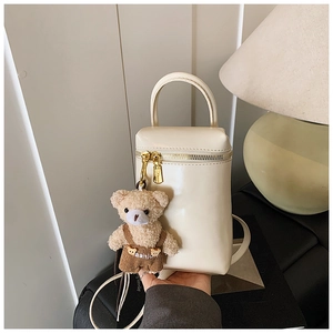 Détail du sac à main en cuir crème avec un joli pendentif en peluche d'ours