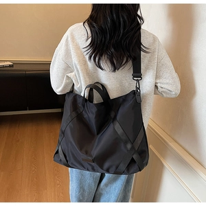 Rückansicht eines Modells mit einer großen schwarzen Reisetasche aus Nylon mit Gurt