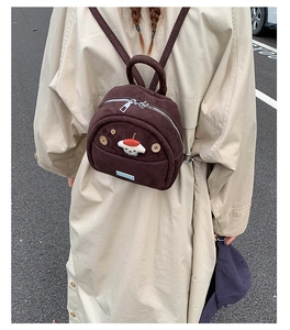 Close-up of mini dark brown corduroy backpack featuring a cute white dog and mushroom
