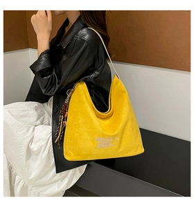 Detail of yellow velvet tote bag featuring nice to meet friends embroidery and tassel charm