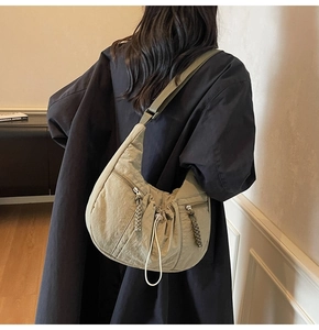 Detailed back view of a pleated olive green nylon crossbody crescent bag on a model