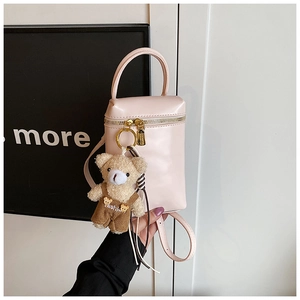 Détail du mini sac à main rose clair avec un pendentif ours en peluche et zips dorés