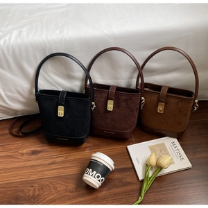 Detail of faux suede bucket bags with leather handles and straps in three colors