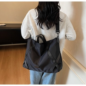 Detail einer großen schwarzen Reisetasche mit verstärkten Gurten und abnehmbarem Schultergurt