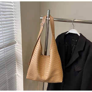 Détail de la texture tressée d'un sac cabas camel avec bandoulière large réglable