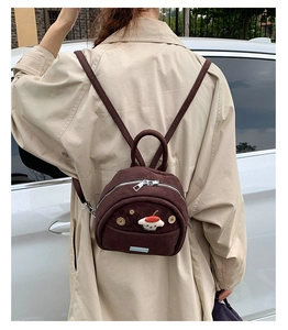 Detail view of mini dark brown suede backpack featuring a cute 3D puppy plush ornament