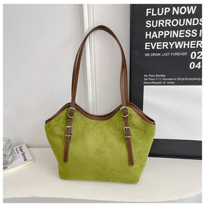 Detailed view of the green suede tote bag with brown leather straps and silver buckles