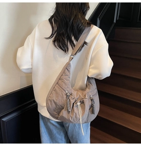 Rear view of model wearing a large grey-brown crescent hobo bag on minimalist stairs