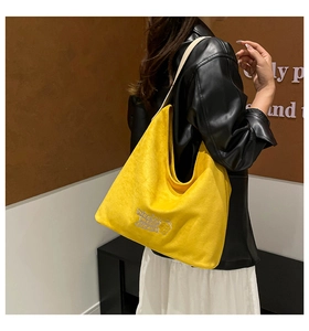 Close-up of mango yellow hobo bag featuring white embroidery text and cartoon bear detail