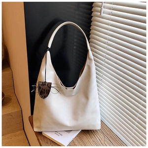 Detail of minimalist cream tote bag with leopard print eyewear case on wood surface