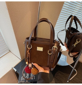 Detail of dark brown suede crossbody bag with mirror reflection and plush charms