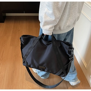 Detailansicht der schwarzen Reisetasche aus Nylon mit Tragegriffen und abnehmbarem Gurt