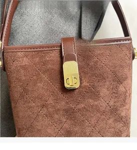 Close-up of brown suede bucket bag featuring quilted diamond pattern and gold twist lock