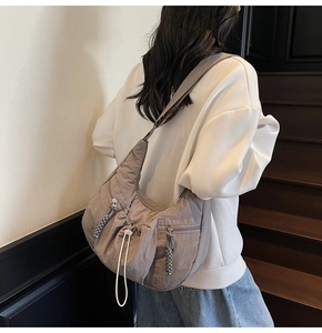 Side view of taupe nylon crescent crossbody bag with drawstring pocket on a model