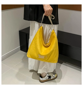 Detail of yellow suede tote bag with white wide shoulder strap and embroidery