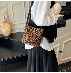 Détail du sac seau en daim léopard avec une fine bandoulière en cuir marron