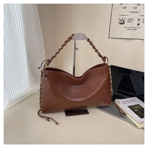Détail du sac hobo vintage marron avec poignée tressée et laçage décoratif latéral