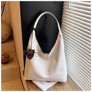 Detail of a large white leather tote bag with a leopard print case on wooden steps