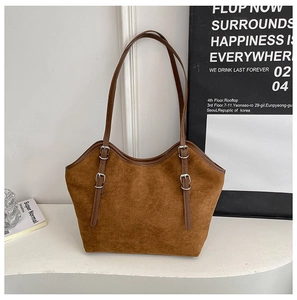Close-up of brown suede tote bag featuring silver metal buckles and matte texture detail