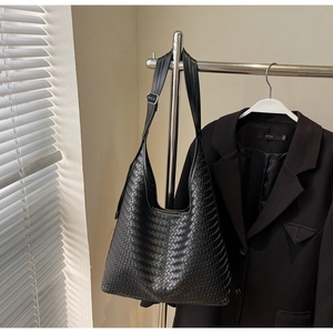 Détail de la texture tressée noire d'un sac hobo minimaliste avec silhouette en croissant