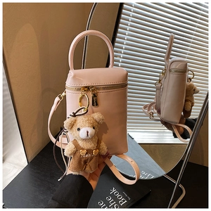 Détail d'un petit sac à main rose avec zip doré et pendentif d'ours en peluche doux