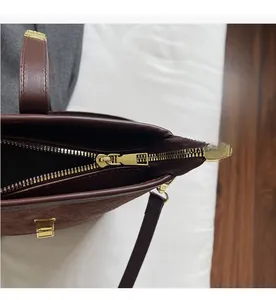 Detailed close-up of the smooth gold zipper and matte brown suede on a bucket bag