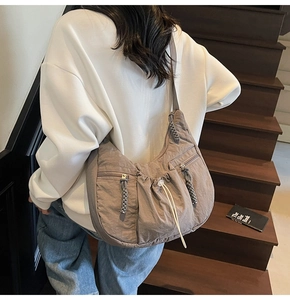 Detail of taupe pleated nylon hobo bag showing woven zipper pulls and drawstring pocket